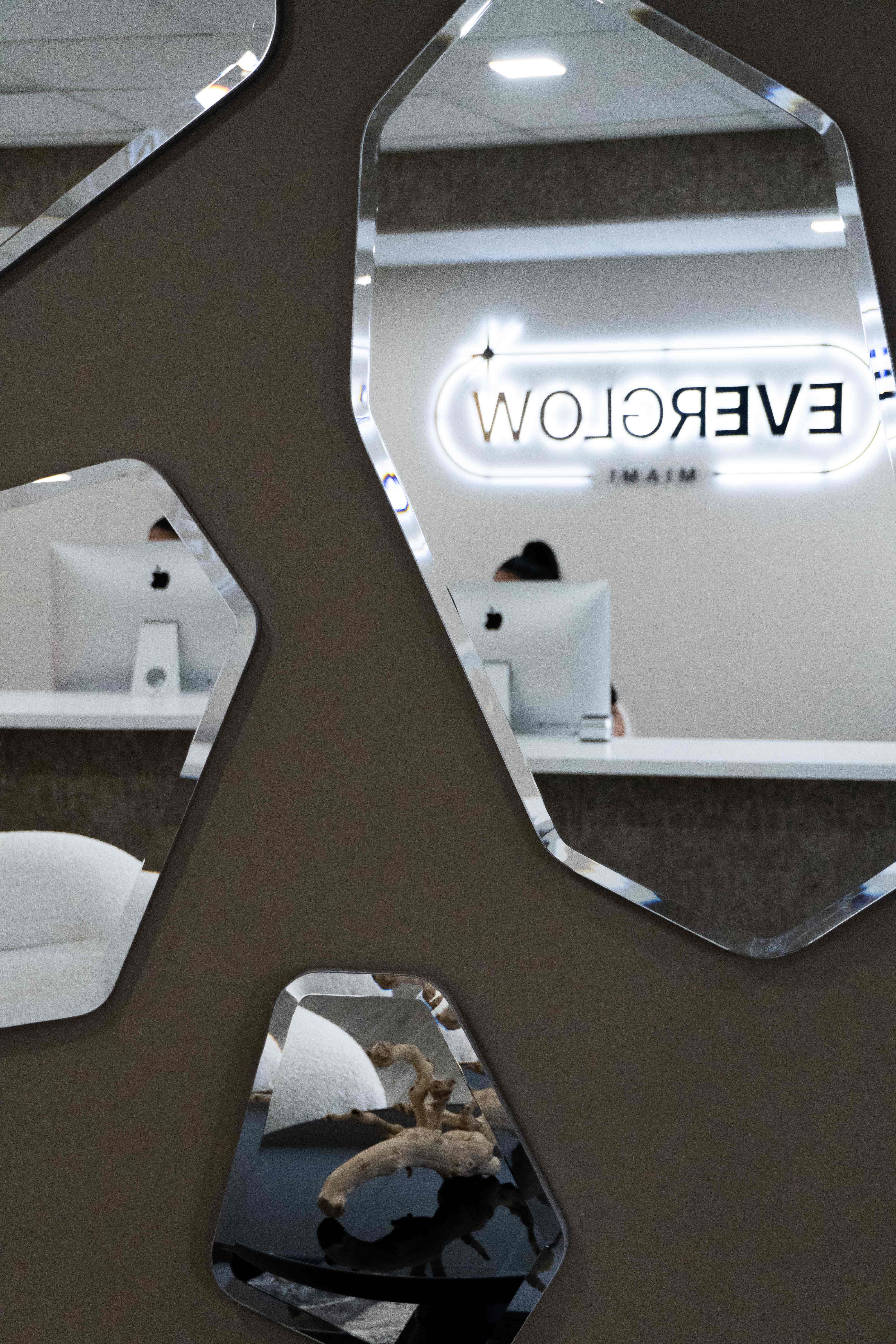 Everglow Miami office interior with decorative mirrors reflecting the illuminated logo